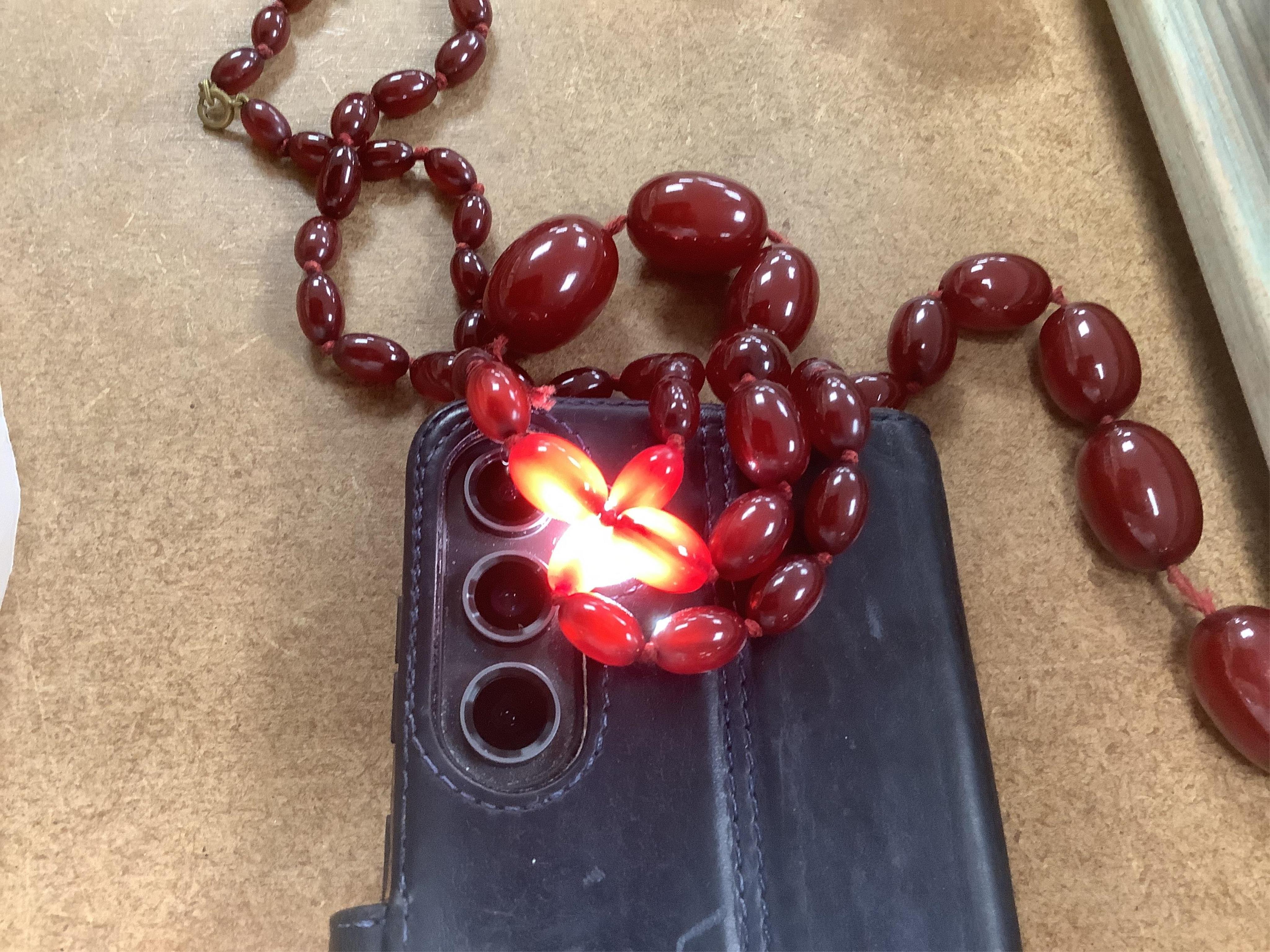 A single strand graduated simulated oval cherry amber bead necklace, string broken, gross weight 73 grams.
